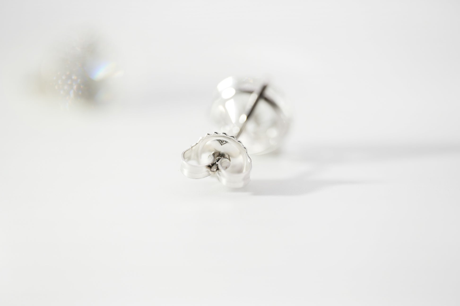 White gold stud earrings on a light gray background