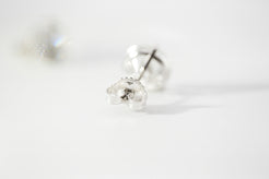White gold stud earrings on a light gray background