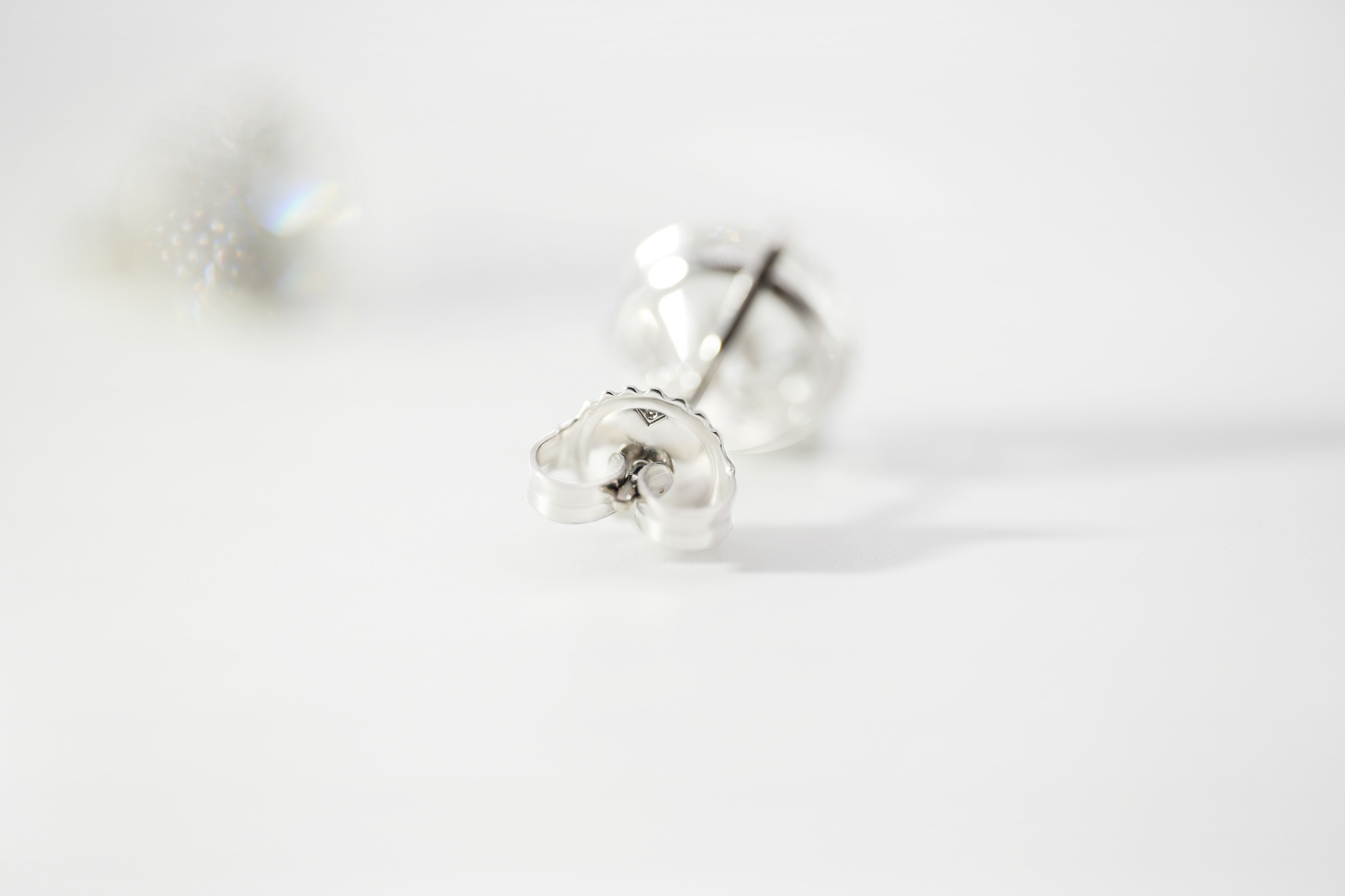 White gold stud earrings on a light gray background