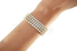 Gold diamond tennis bracelet on a wrist against a white background