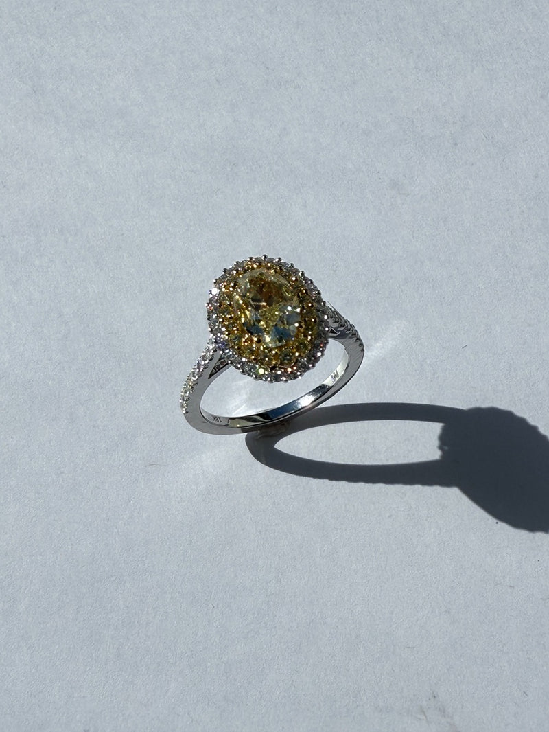 White gold ring with a yellow gemstone on a light gray background