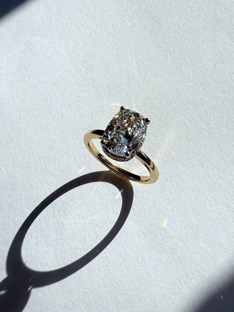 Gold engagement ring with a large diamond on a light gray background