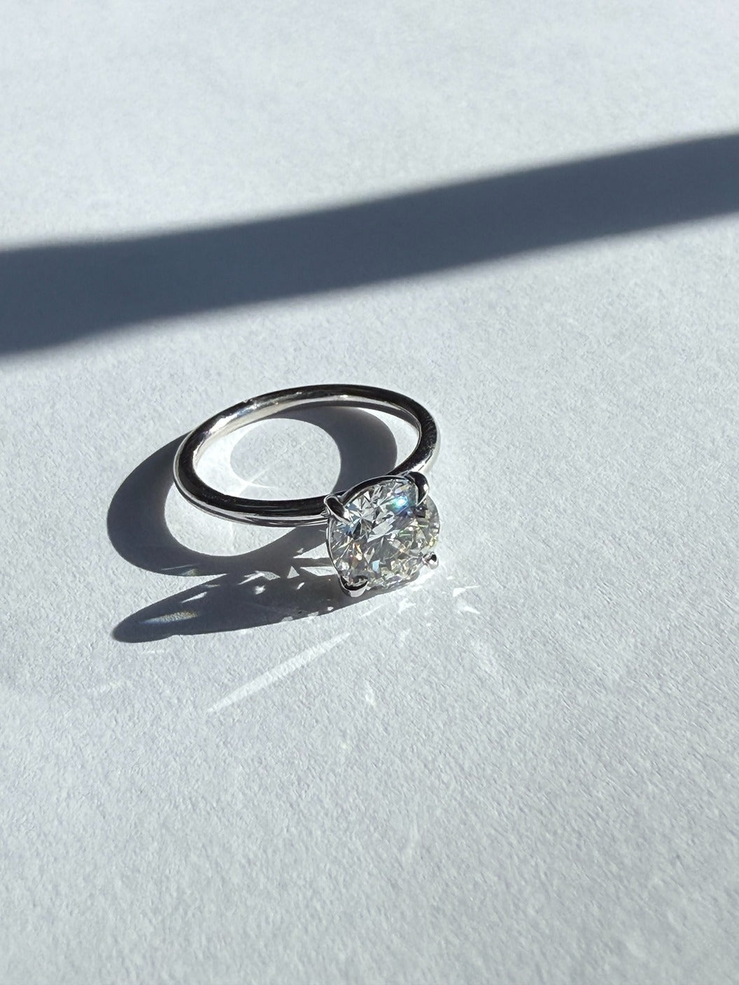 White godl engagement ring with a diamond on a light surface