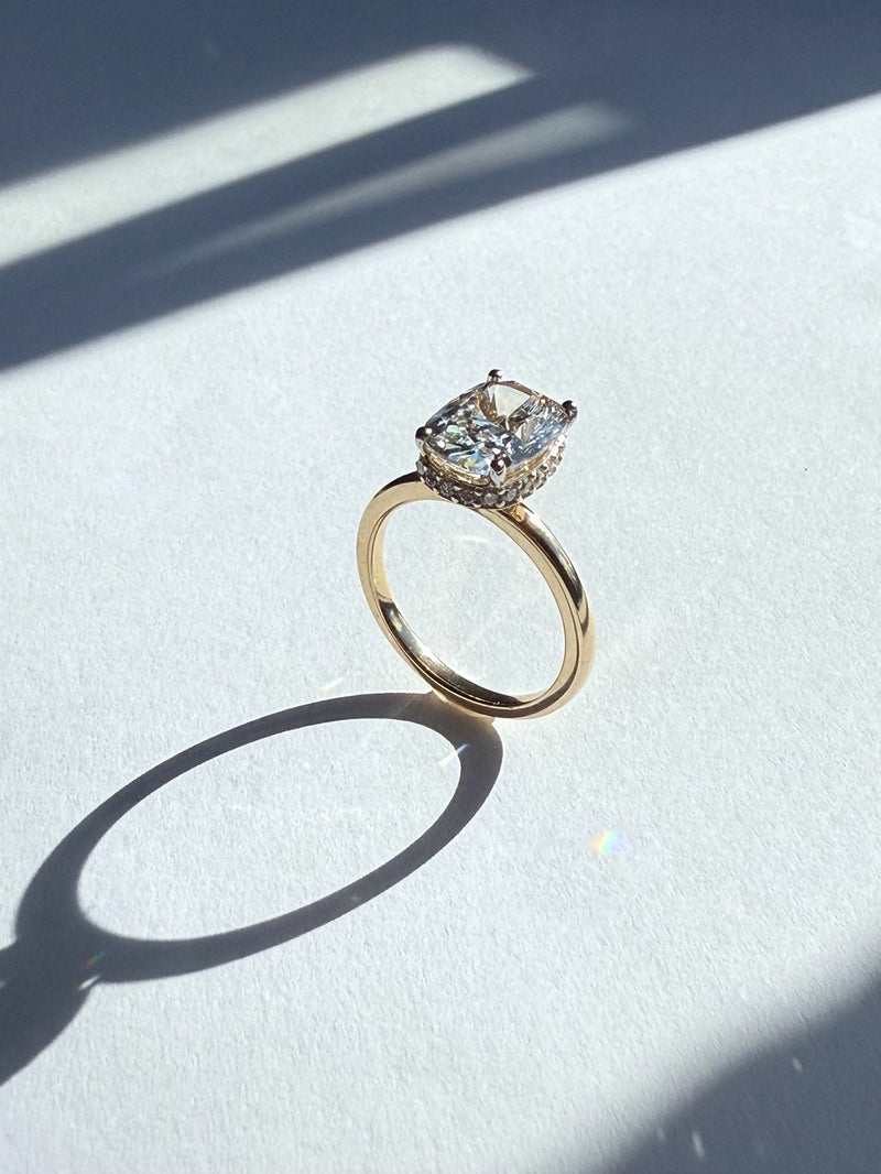 Bespoke gold engagement ring with a large diamond on a white surface 
