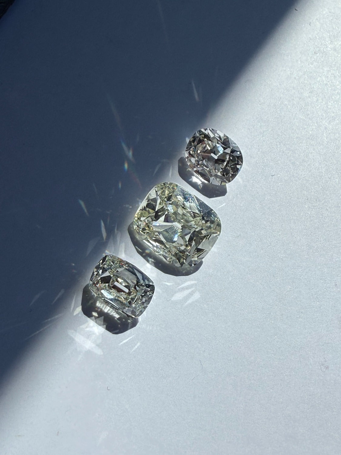 Three diamonds of different shapes and sizes on a reflective surface