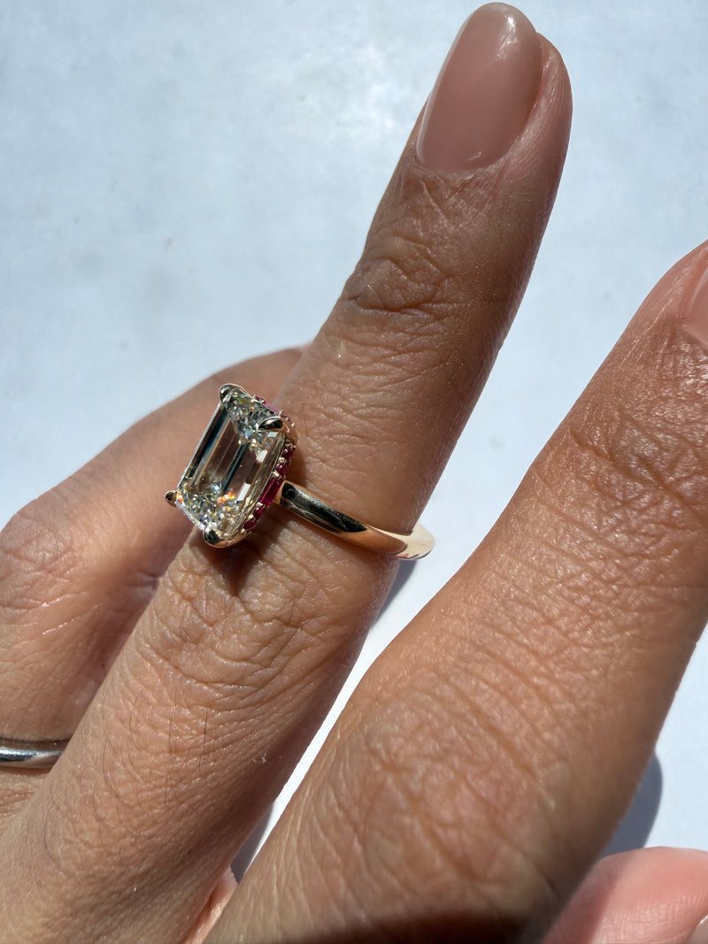 CLOSE UP OF EMERALD DIAMOND RING WITH RUBY HIDDEN HALO