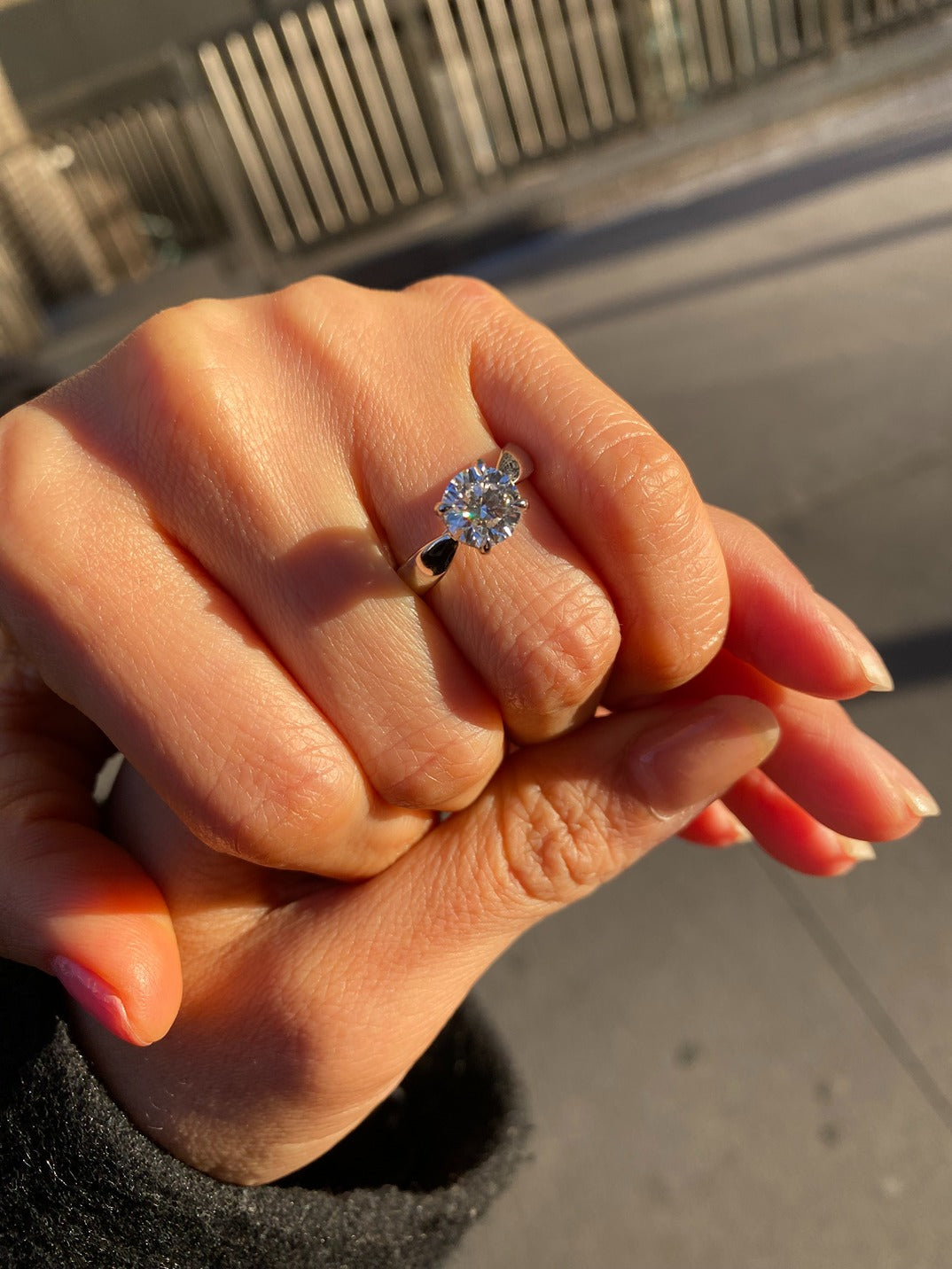 Close-up of a hand wearing a diamond ring with a blurred background