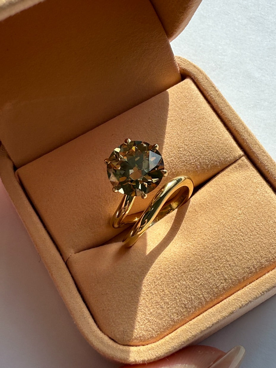 Gold ring with a circular gemstone in a jewelry box