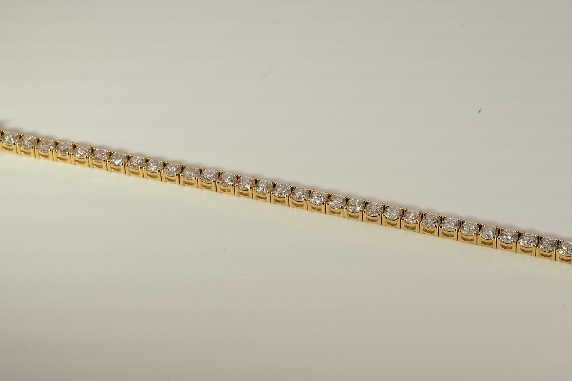 Gold tennis bracelet on a beige background