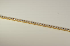 Gold tennis bracelet on a beige background