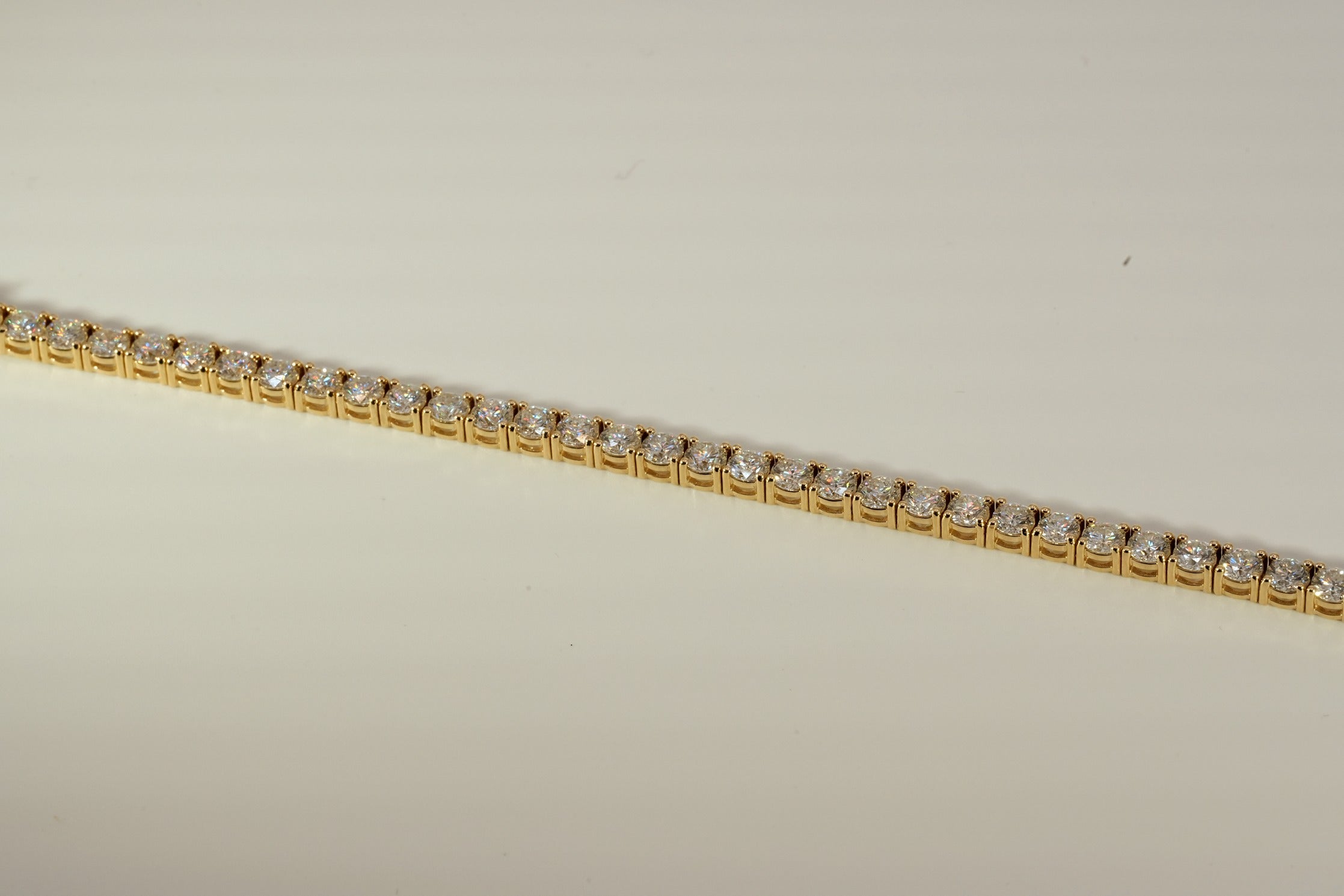 Gold tennis bracelet on a beige background