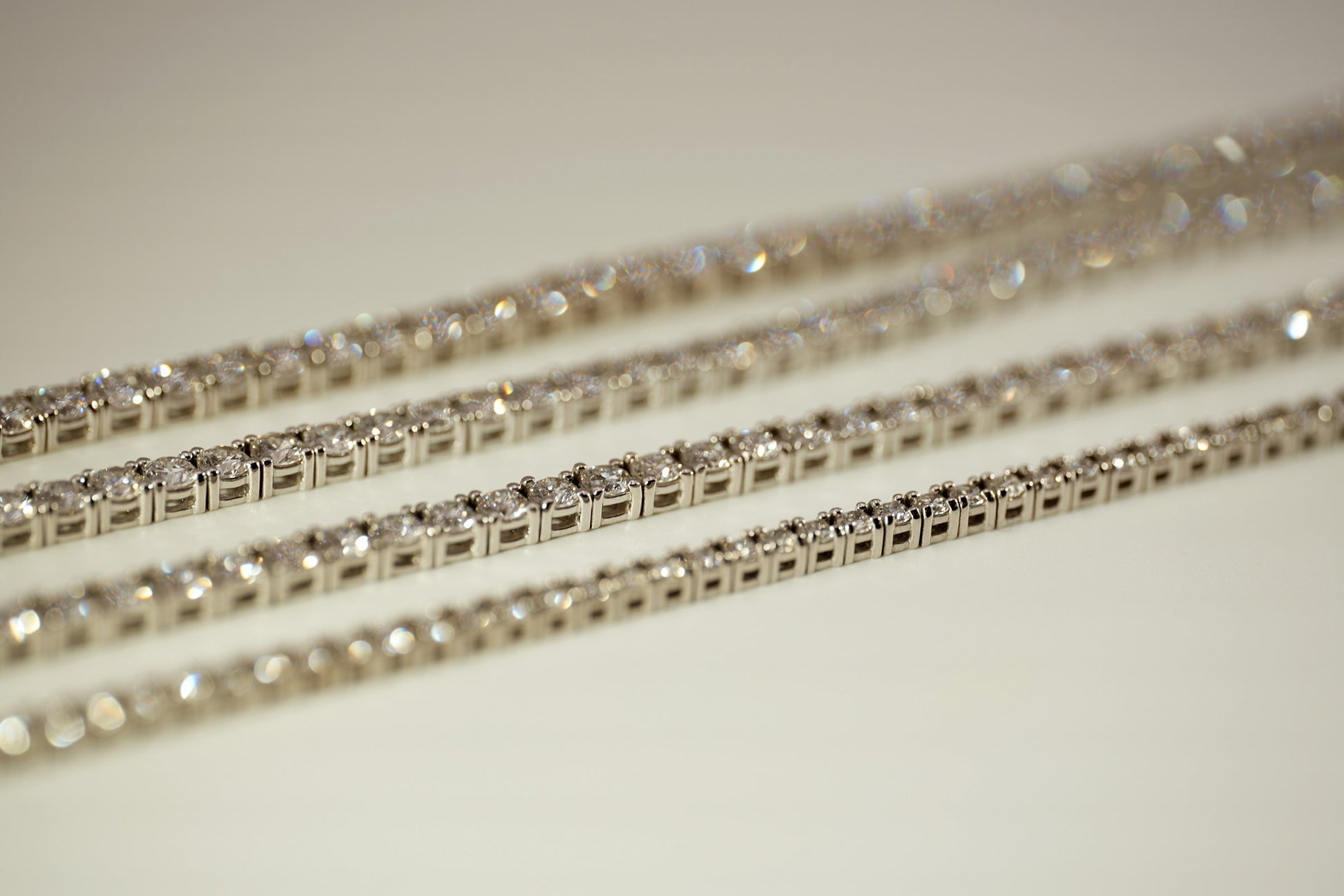 Set of gold tennis bracelets on a neutral background