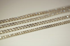Set of gold tennis bracelets on a neutral background
