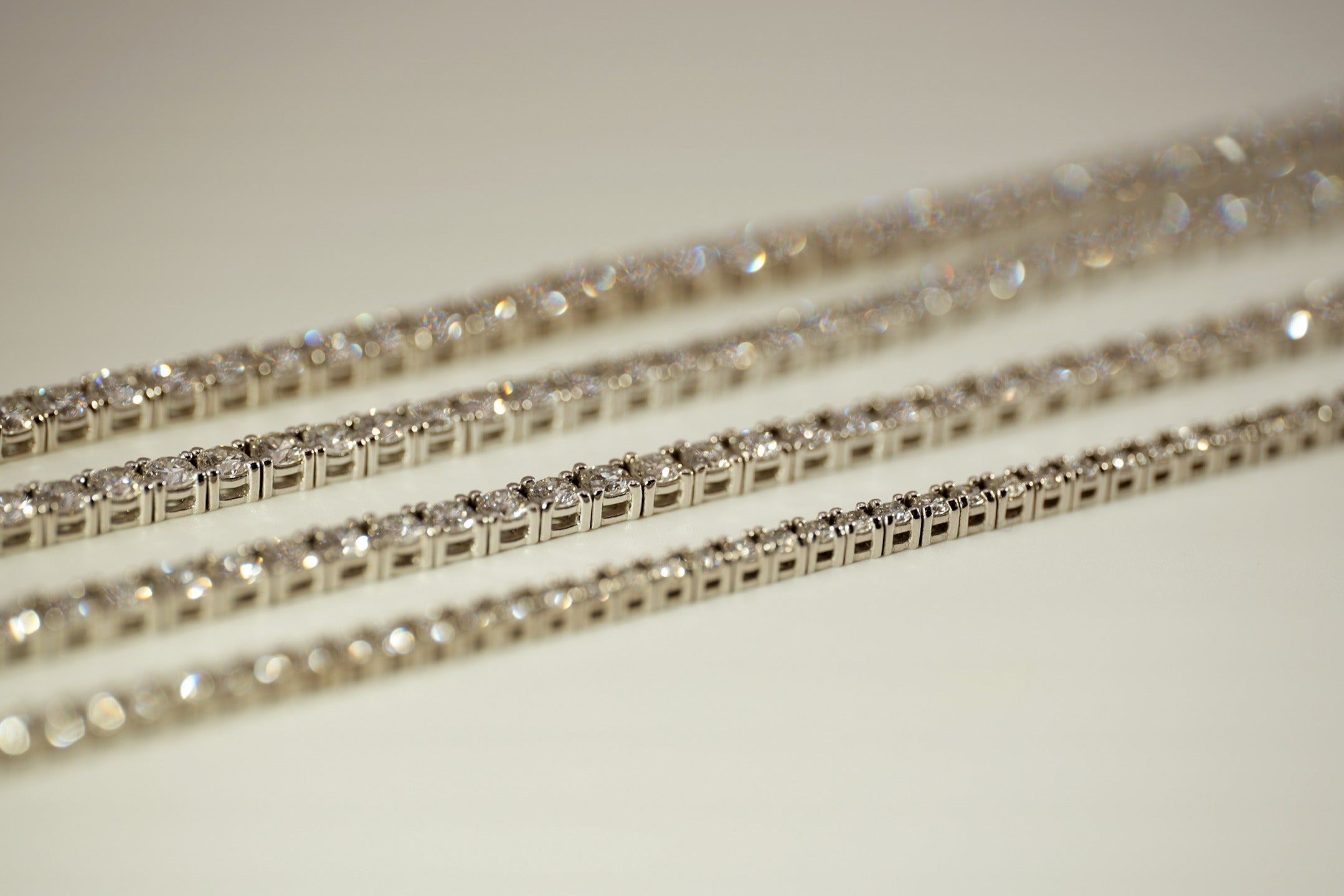 Set of gold tennis bracelets on a neutral background