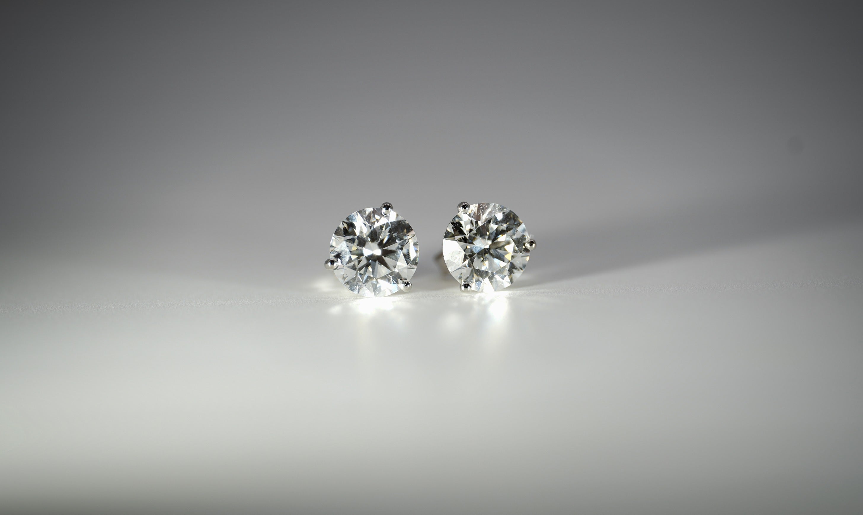Pair of diamond stud earrings on a gray background